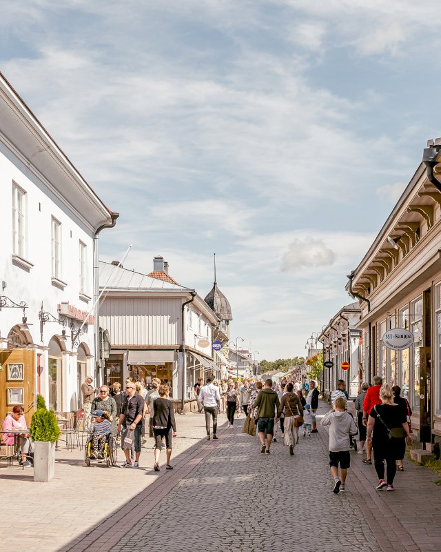 Paljon ihmisiä kävelemässä mukulakivikadulla Vanhan Rauman puutaloalueella.