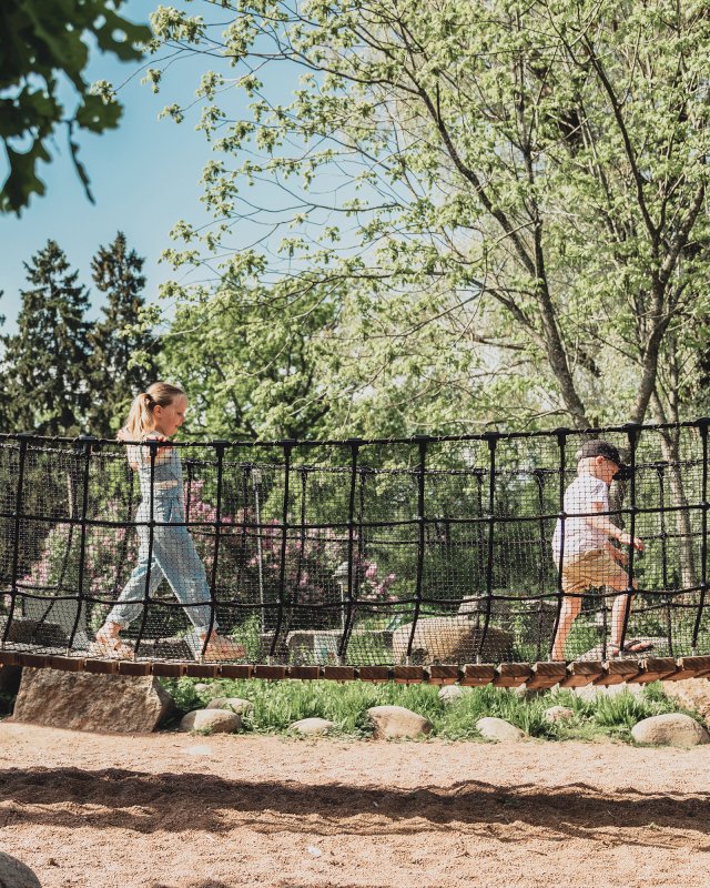 Tyttö ja poika kävelevät riippusiltamaista temppurataa pitkin.